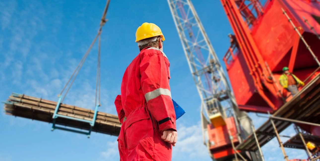 Une personne au pied d'une grue, transportant des matériaux de construction sur un chantier