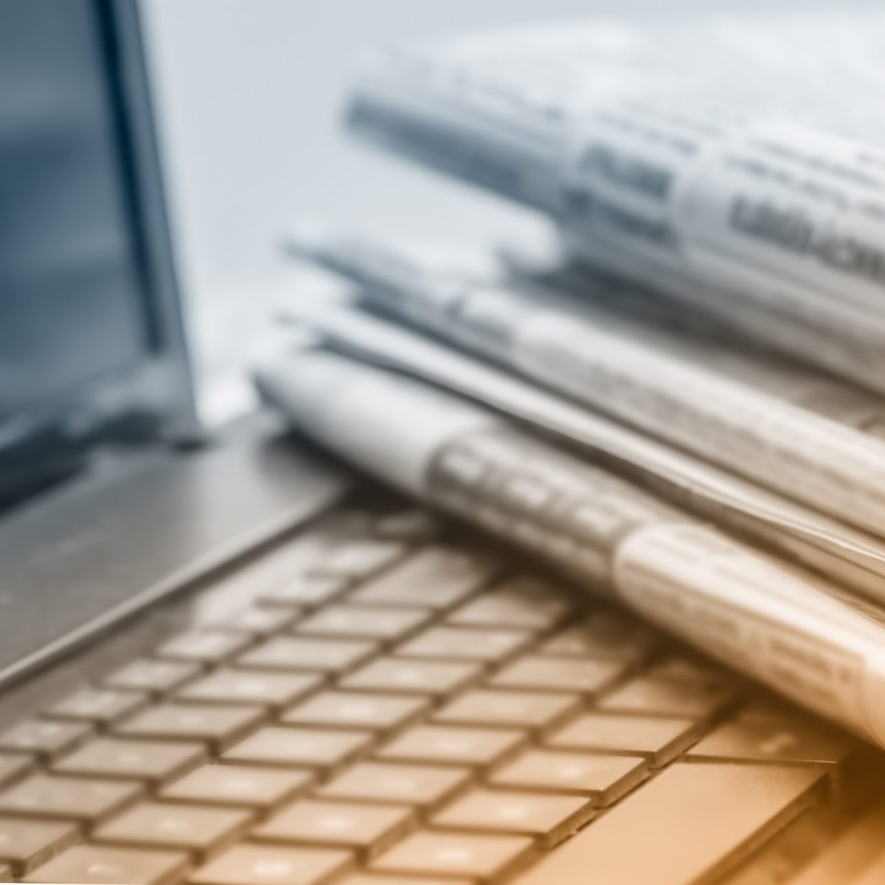 image de journaux posés sur un ordinateur pour représenter le sourcing dans de nombreuses sources presse et digitales