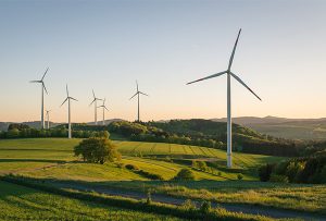 Image d'un parc éolien dans la campagne sous un lever de soleil afin d'illustrer notre article sur les changements et les opportunités de l'éolien dans les marchés publics.