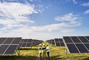 Image de trois personnes entourées de panneaux photovoltaïques afin d'illustrer notre article sur le secteur de l'énergie photovoltaïque dans les marchés publics