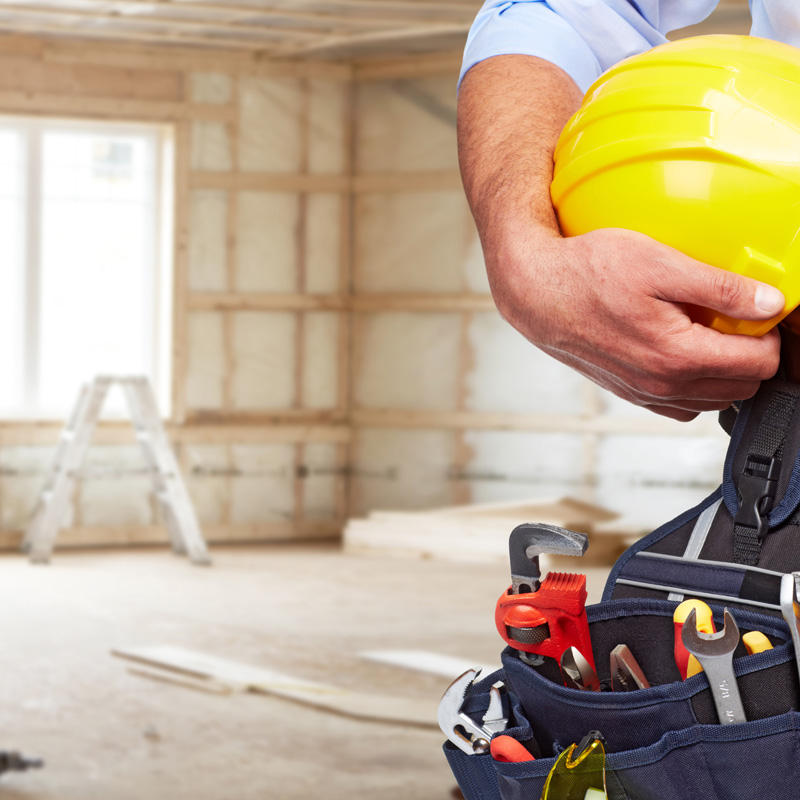 image d'un ouvrier à l'intérieur d'un chantier, au moment de la pose des plaques de plâtres aux murs